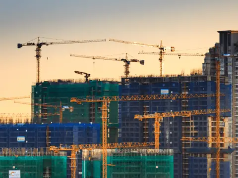 Large construction site with tower cranes at sunset